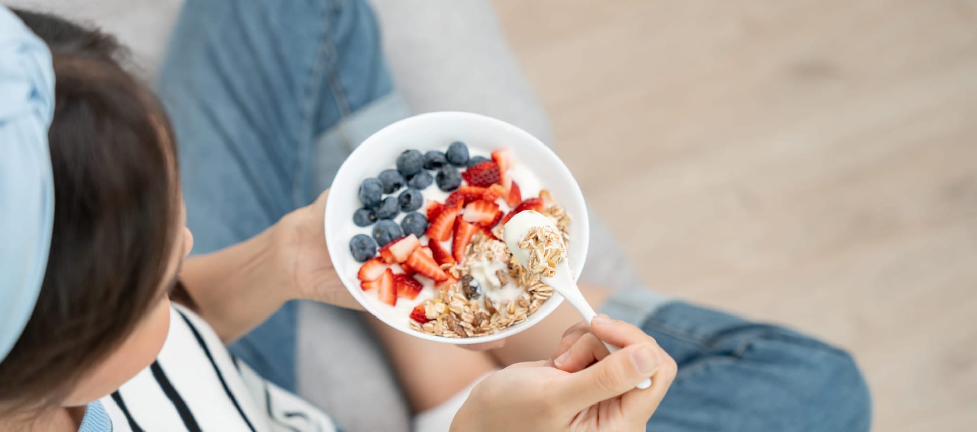 A woman holding a bowl of oats, strawberries, blueberries and milk, a healthy breakfast that's good for the gut.