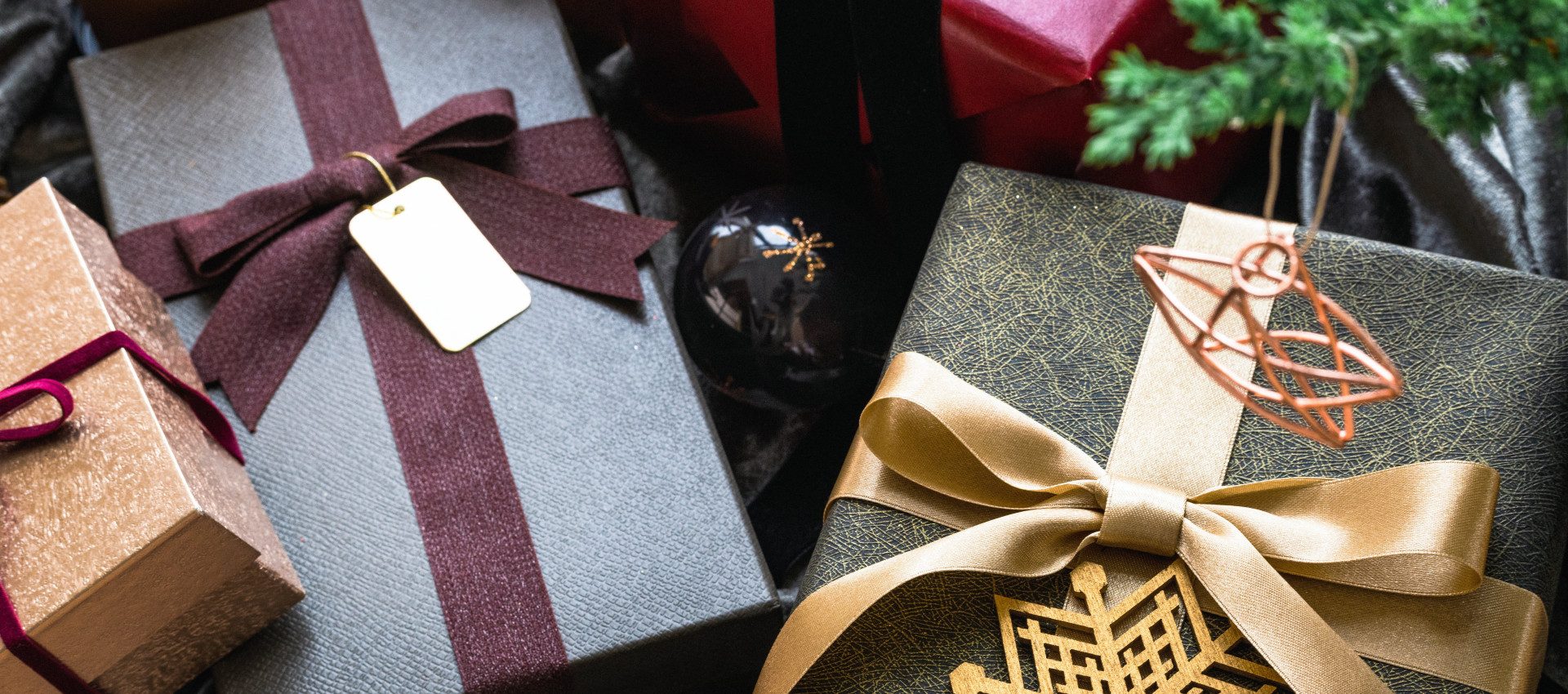 An image showing multiple wrapped Christmas gifts, with ribbons and golden stars in festive greens and burgundy colours.