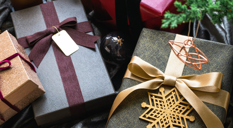 An image showing multiple wrapped Christmas gifts, with ribbons and golden stars in festive greens and burgundy colours.