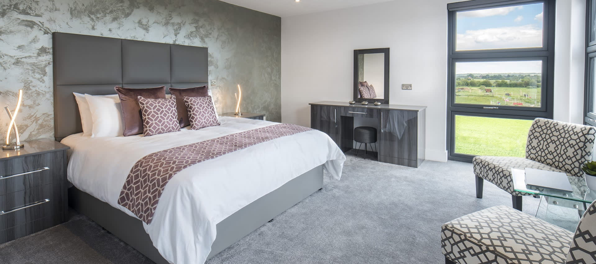 Bed, desk and chairs in room, with view from window