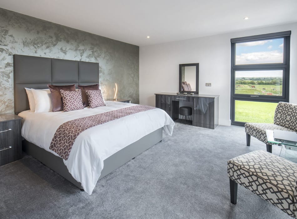 Bed, desk and chairs in room, with view from window