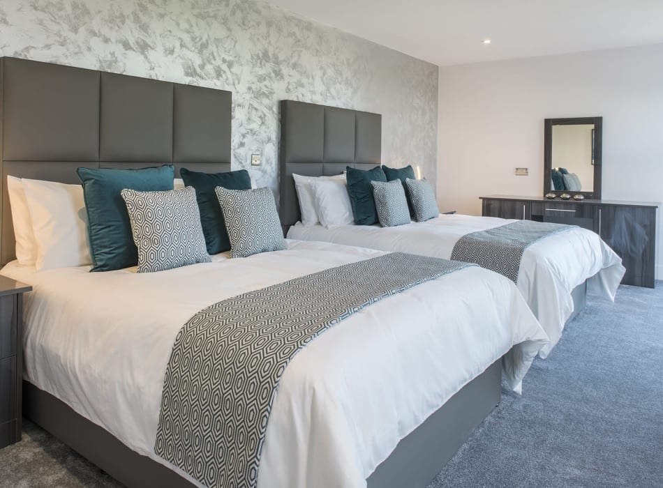 Two beds in room with desk